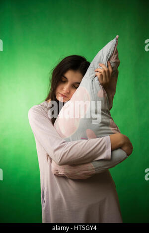 Una ragazza in un nightgown appoggiato contro il cuscino su una verde chroma key sullo sfondo Foto Stock