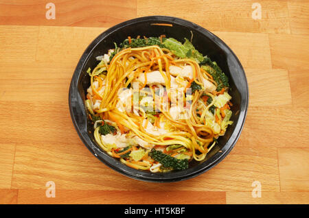 Pollo Chow Mein in un astuccio di plastica su una cucina in legno piano di lavoro Foto Stock