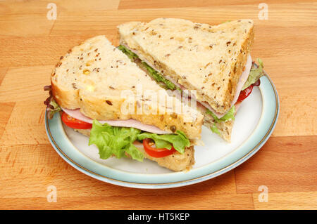 Fresca insalata di prosciutto sandwich made con pane seminate su una piastra su un tavolo in legno Foto Stock