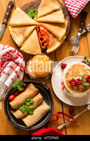 Vari tipi di crepes e pancakes su tavola in legno rustico, vista dall'alto Foto Stock