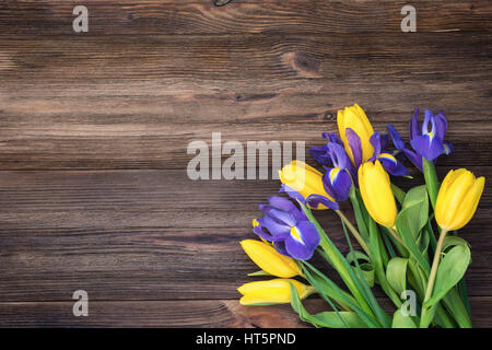 Bouquet di fiori. Tulipani gialli e iride fiori su legno rustico sfondo. Table top visualizzare e copiare lo spazio per testo Foto Stock