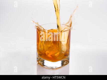 Splash in bicchiere di scotch whisky con cubetti di ghiaccio Foto Stock