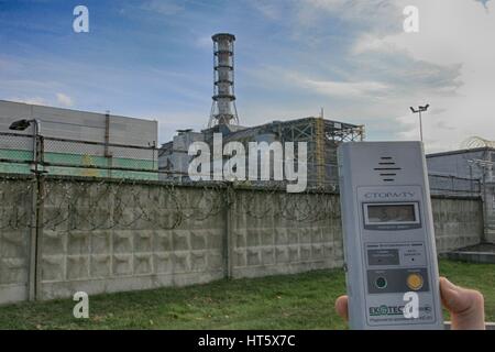 Il dosimetro mostrando elevata radioattività nella centrale nucleare di Chernobyl con il reattore esploso 4 in background Foto Stock