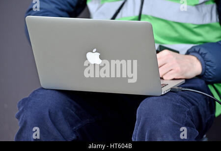 Fotografo utilizzando un MacBook Pro Apple computer portatile per inviare le immagini dal lato del campo di calcio Foto Stock