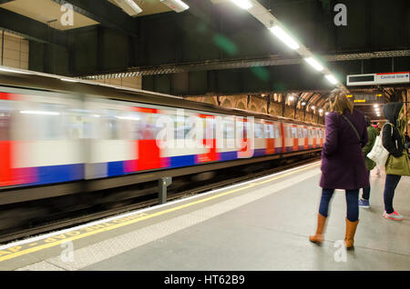 In attesa di velocizzare la metropolitana di Londra con il treno alla stazione della metropolitana platform Foto Stock