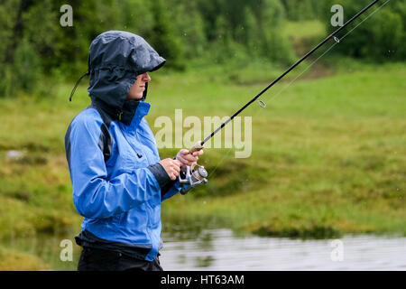 Donna con la canna da pesca in condizioni di tempo piovoso Foto Stock