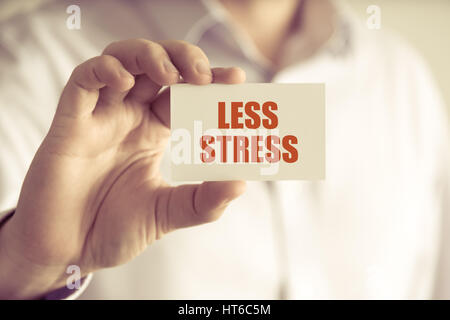 Primo piano su imprenditore tenendo una scheda con il testo MENO STRESS, business Concetto di immagine con soft focus background e tono vintage Foto Stock