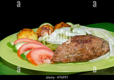 Kebab macinata di maiale con verdure e patate, su sfondo nero Foto Stock