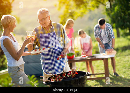 La famiglia felice avente un barbecue sul campeggio Foto Stock