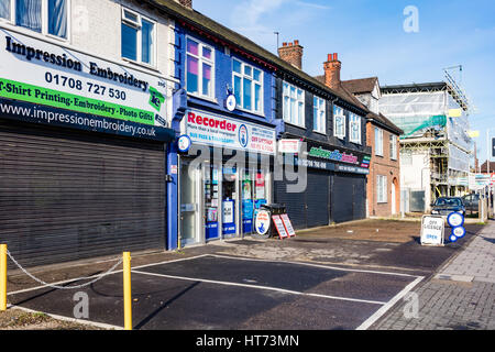 Una sfilata di negozi sulla A125 North Street, Romford, alcuni chiuso al mattino presto con un aperto il giornalaio, London, Regno Unito Foto Stock