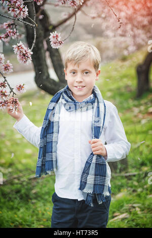 Carino giovane ragazzo in una fioritura frutteti di mandorla Foto Stock