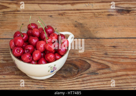 Ripe organic homegrown ciliege in un vintage vaso in ceramica, su sfondo di legno Foto Stock
