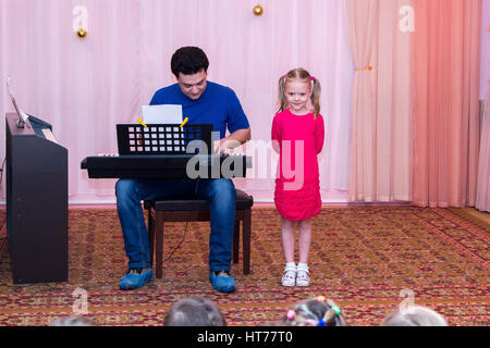 Ragazza canta mentre suo padre suona il sintetizzatore Foto Stock