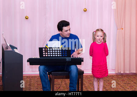 Ragazza canta mentre suo padre suona il sintetizzatore Foto Stock