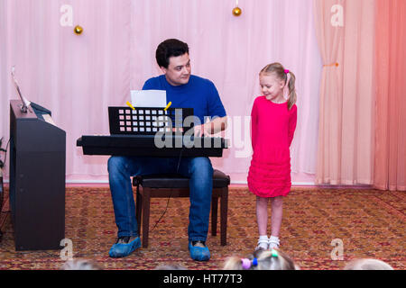 Ragazza canta mentre suo padre suona il sintetizzatore Foto Stock