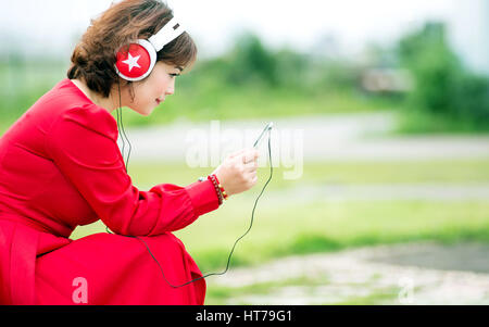 Donna felice navigando tablet e ascoltare musica su cuffie a casa Foto Stock