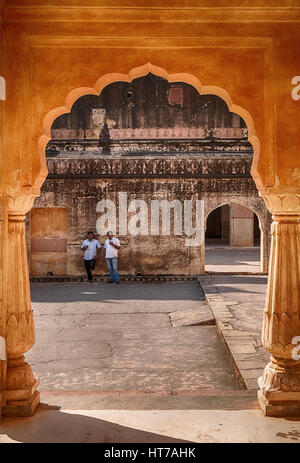 Amer, India - 18 novembre 2016: due uomini, appoggiato contro una parete, può essere visto attraverso un arco del padiglione o baradari, dell'uomo singh palace Foto Stock