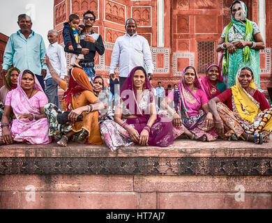 Agra, India - 19 novembre 2016: un gruppo di uomini e donne in visita al Taj Mahal sedersi vicino all'ingresso della porta grande (darwaja) in Agra, India. Foto Stock