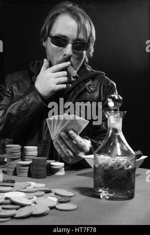 Foto di un uomo giocando a poker indossando occhiali da sole e fumare un sigaro. Foto Stock