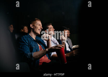 Sorridente giovane con gli amici nella sala cinema guardare film. Gruppo di persone che guardano film in teatro. Foto Stock