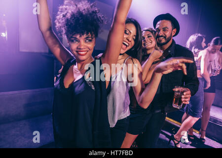 Gruppo di amici dancing in night club. Giovani uomini e donne divertendosi in discoteca. Foto Stock