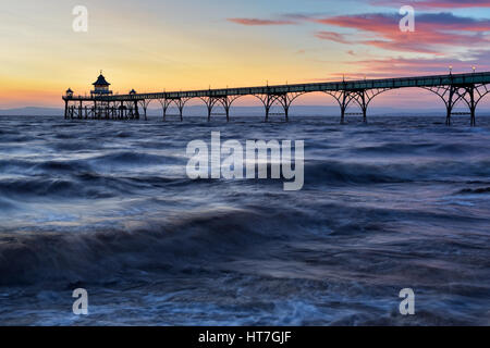 Tramonto a Clevedon Pier nel Somerset, Regno Unito prese con un lento rilascio otturatore dando il mare un effetto seta. Foto Stock