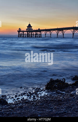 Tramonto a Clevedon Pier nel Somerset, Regno Unito prese con un lento rilascio otturatore dando il mare un effetto seta. Foto Stock