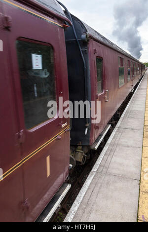 Il vecchio treno a vapore con carrozze ferroviarie in British Railways colori arrivando a una piattaforma della stazione. Nottingham patrimonio centro di trasporto, England, Regno Unito Foto Stock