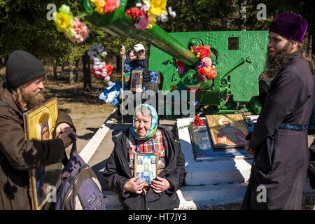Persone tenere icone religiose nei pressi di un cannone in Russia Foto Stock