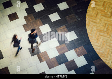 Due persone che camminano in un edificio pubblico hall vista dall'alto. Motion Blur tecnica di bassa velocità shot. Blur sagome di persone. Un otturatore a bassa velocità shot. Foto Stock