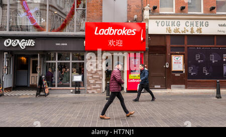 Ladbrokes agenzia di scommesse store branch in Wardour Street, Chinatown, London, Regno Unito con la gente che camminava e O'Neill's pub accanto ad esso Foto Stock