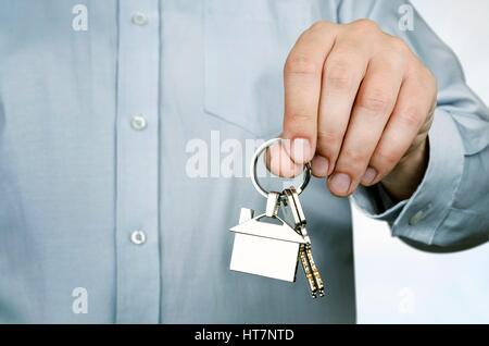 Agente immobiliare tenendo premuto i tasti per casa nuova. Home forma pendente al cromo Foto Stock