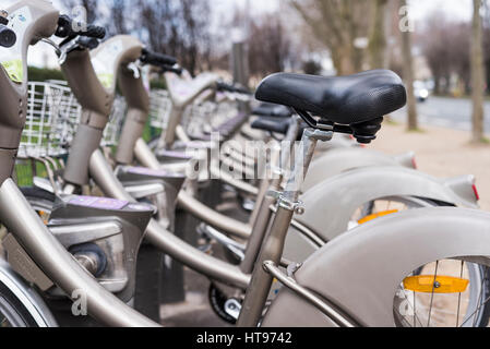 Un nero sella per bicicletta spicca in una fila di Velib noleggio biciclette in Parigi Francia. Foto Stock