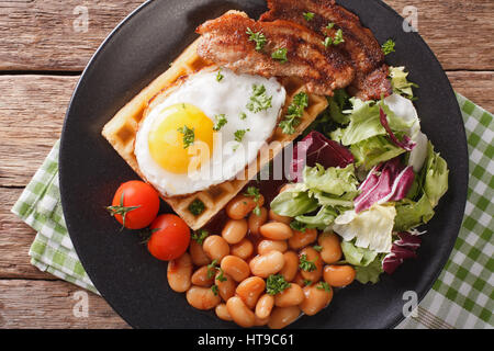 Colazione abbondante con uova fritte, cialde, pancetta, mix insalata di fagioli e vicino sul tavolo. vista orizzontale dal di sopra Foto Stock