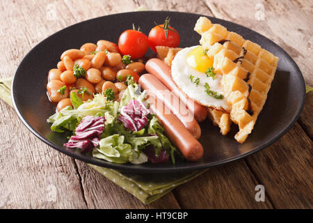 Frittelle fritte con uova, salsicce, fagioli e insalata fresca close-up su una piastra orizzontale. Foto Stock