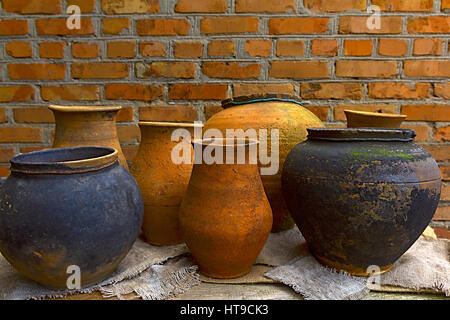 Ceramica vasi di argilla, in piedi su un tavolo di legno su uno sfondo di un muro di mattoni Foto Stock