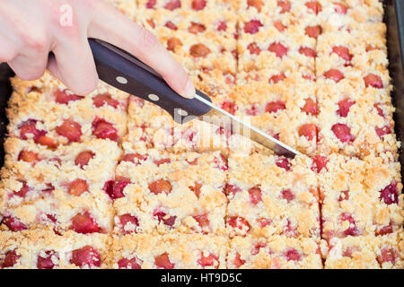 Persona di taglio in casa dolce crumble torta di ciliegie Foto Stock