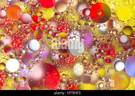 Retroilluminato con gocce di olio galleggiante in acqua su perline colorate Foto Stock