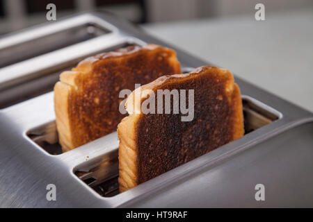 Due fette di toast bruciato in un metallo tostapane. Foto Stock