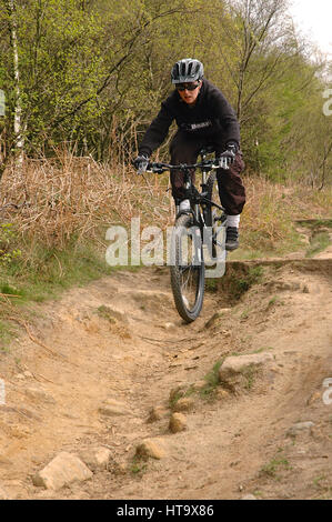 Giovane donna su una mountain bike in campagna Foto Stock