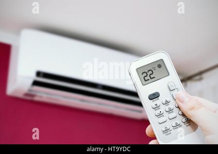 Condizionatore split a parete. Mano che tiene il controllo remoto Foto Stock