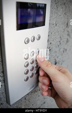 Close up del dito che preme il pulsante Interfono sul tastierino numerico Foto Stock