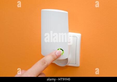 Ripetitore WiFi nella presa elettrica sulla parete arancione. Modo semplice per estendere la rete wireless in casa Foto Stock