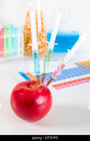 Tre siringhe in rosso apple. Alimenti geneticamente modificati in lab concept. Foto Stock