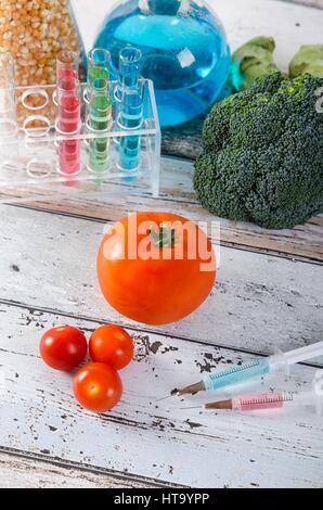 La siringa e il pomodoro. Alimenti geneticamente modificati concetto Foto Stock