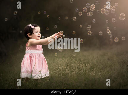 Bambina cercando di catturare le bolle di sapone Foto stock - Alamy