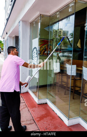 Florida South,Miami Beach,Washington Avenue,storefront,vetro,adulti uomo uomini uomini uomini uomini uomini uomini, lavoro,lavoro,lavoratore,pulizia,finestra pulizia,squeegee,visitatori tr Foto Stock