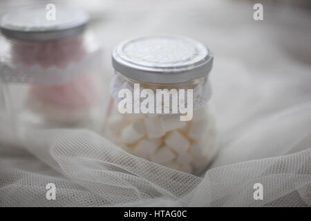 Marshmallows in un vasetto di vetro su un panno bianco. Primo piano Foto Stock