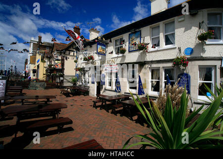 Tabelle vuote al di fuori del classico pub inglese in un giorno d'estate con fiori e cielo blu. Foto Stock