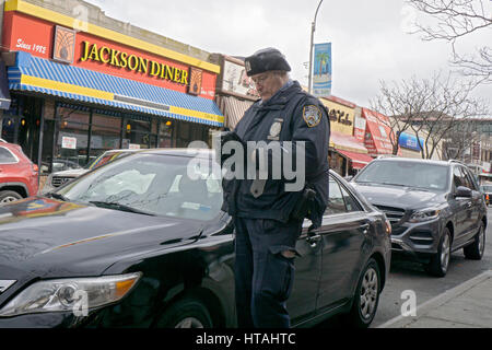 A New York City il traffico poliziotto scrivendo un biglietto per una vettura con un parcheggio violazione sulla 74a Strada di Jackson Heights, Queens, a New York City. Foto Stock